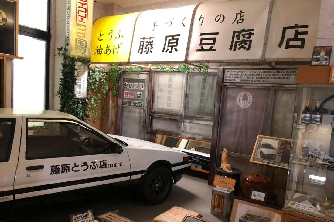 Recreated Fujiwara Tofu Shop storefront with a white-and-black AE86 parked outside, the centerpiece stop on this Initial D tour in Gunma